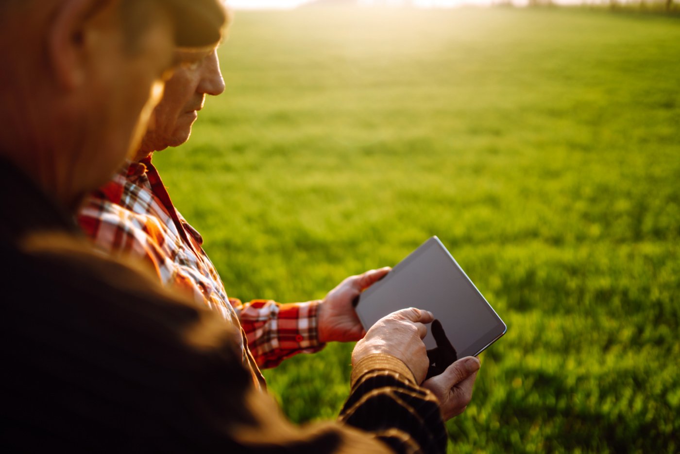 Two farmers in field holding tablet